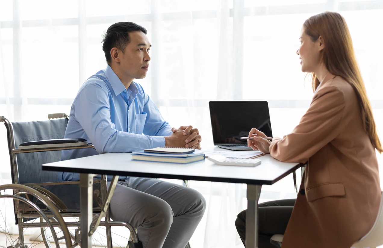 Man in wheelchair talking to female manager in office about recruitment and job interview